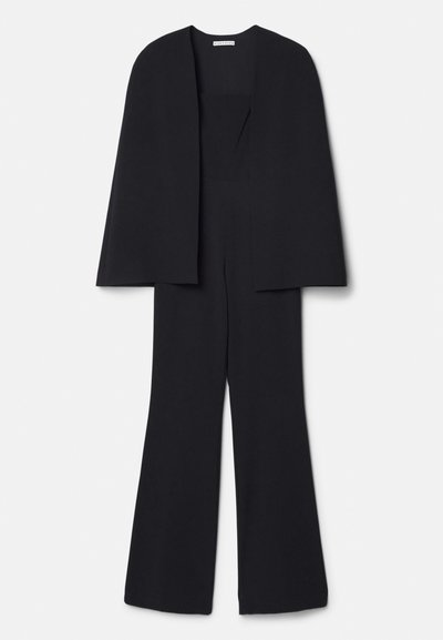 Combinaison noire avec un design de cape, présentant une coupe à jambes larges, une texture unie et un col sans couture, adaptée pour des occasions formelles.