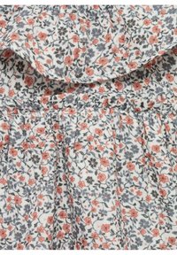 Robe florale avec un fond blanc, ornée de petites fleurs roses et bleues, en coton texturé, taille froncée et décolleté volanté.
