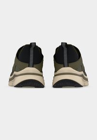 Αθλητικά παπούτσια σε ελιά πράσινο χρώμα με μαύρο επάνω μέρος, που διαθέτουν υφασμένη εσωτερική σόλα από καουτσούκ, μια παχιά κρεμ ρίγα στη μέση της σόλας και μια κάθετη ριγέ ετικέτα.