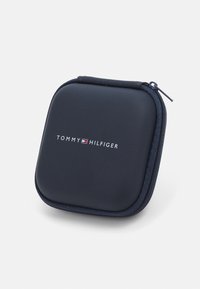 Funda rígida navy de Tommy Hilfiger con cremallera, textura suave, forma cuadrada, logo impreso en blanco, con una cremallera y tirador azul.
