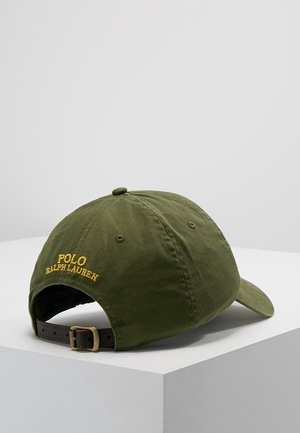 Olijfgroene Polo Ralph Lauren honkbalpet met verstelbare bruine leren band en geel geborduurd logo aan de achterkant, getoond op een witte ondergrond.