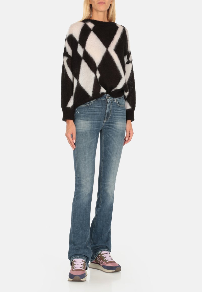 Maglione fluffy a fantasia diamante bianca e nera abbinato a jeans a zampa d'elefante blu e sneakers sportive multicolori con dettagli rosa.