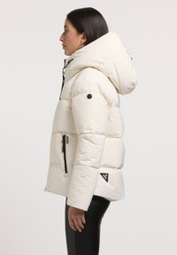 Puffjacke in Off-White mit abnehmbarer Kapuze, seitlichen Reißverschlusstaschen und schwarzen Hardware-Akzenten. Strukturierter, gepolsterter Design.