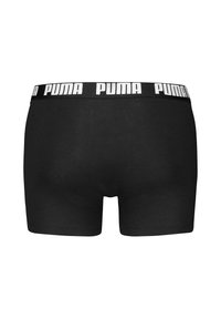 Črne bombažne bokserice z belim blagovnim pasom, na katerem je v debelem tisku napisana "PUMA", ki prikazujejo gladko in prilegajočo se obliko.