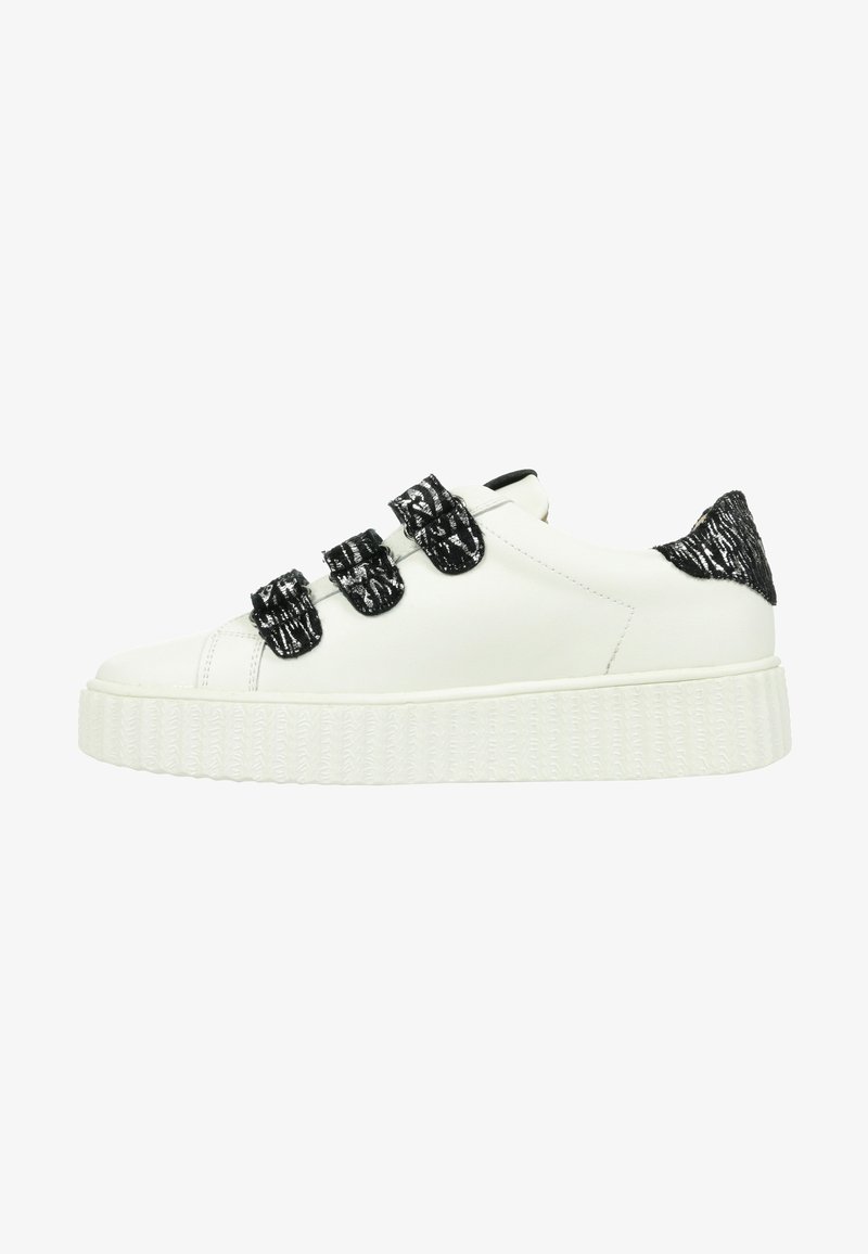 Sneaker en cuir blanc avec trois sangles Velcro à motif noir, accent texturé noir au talon et une épaisse semelle en caoutchouc blanc.