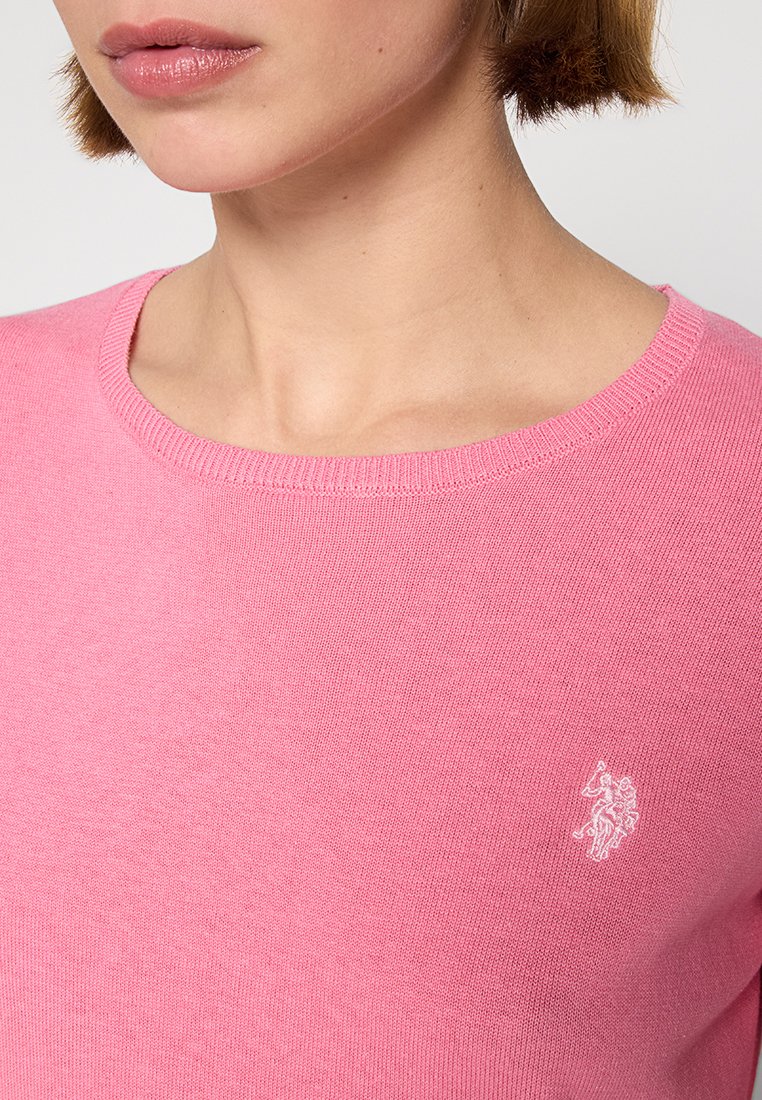 Maglione rosa a maglia con scollatura rotonda e un piccolo logo bianco sul lato sinistro in alto. Texture morbida con una finitura liscia.