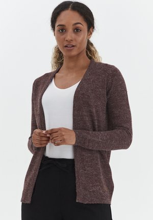 Burgunderstrikket cardigan med lange ermer, åpen frontdesign og ribbestrikkede mansjetter. Båret over en hvit skjorte, med et mykt, teksturert stoff.