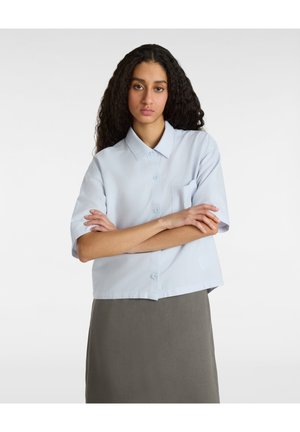 Camisa de manga corta azul clara con cuello, cierre de botones en el frente y un solo bolsillo en el pecho. Tejido suave, diseño corto.