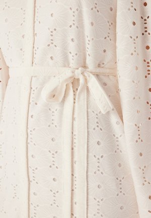 Biała szata z tkaniny z misternym wzorem haftu angielskiego w kwiaty, związywana pasującym paskiem, charakteryzująca się miękkim, teksturowanym wyglądem.