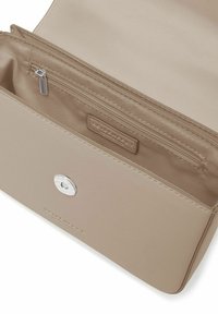 Interno di una borsa a mano sintetica beige con una tasca con cerniera e accessori in argento. Texture liscia con un design minimalista.