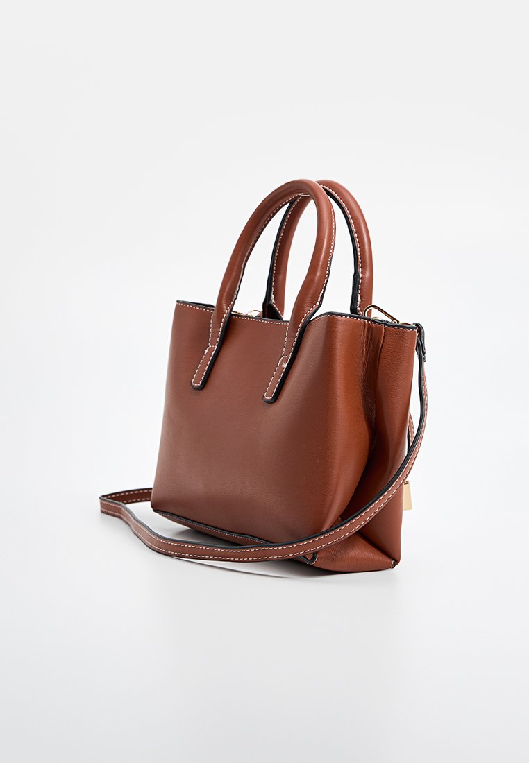 Sac à main en cuir marron avec double anses, bandoulière réglable et coutures contrastées. Design compact avec une texture lisse.