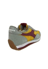 Sneaker con tomaia in suede grigia, accenti gialli e bordeaux, suola in gomma testurizzata e colletto imbottito per il comfort.