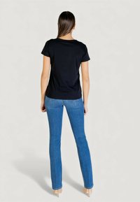 T-shirt noir à manches courtes en tissu doux, coupe ajustée et col rond. Pantalon jean bleu avec une coupe slim et un léger délavage au niveau des genoux.
