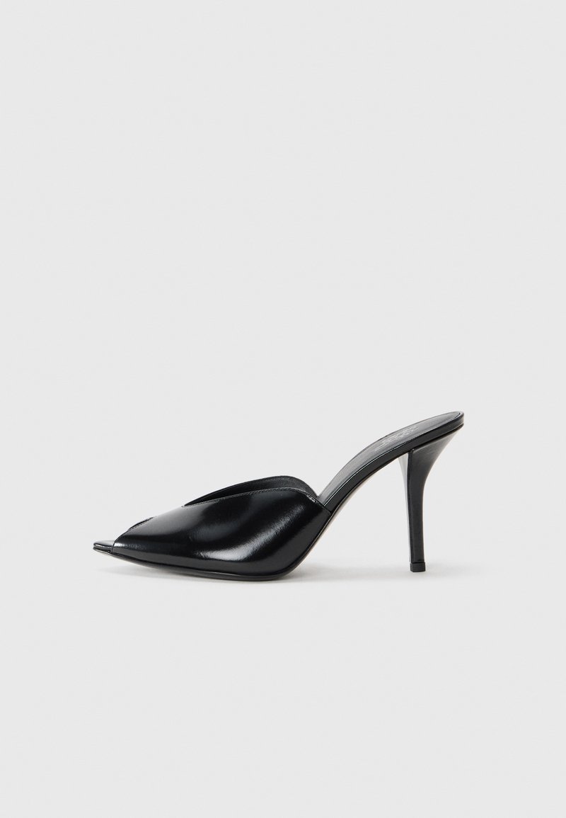 Mules à talons hauts en cuir noir, avec un design à bout ouvert, pointu, texture lisse et un fin talon aiguille.