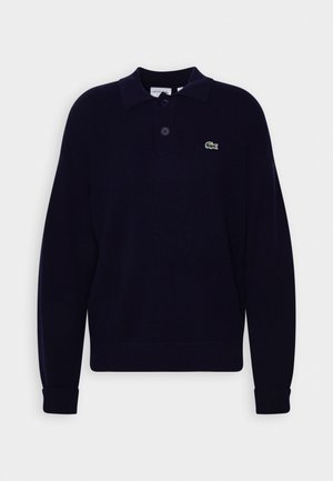 Granatowa, dzianinowa koszulka polo z długim rękawem z dwoma guzikami, z zielonym logo krokodyla Lacoste na lewej piersi, z prążkowanymi mankietami i dołem.