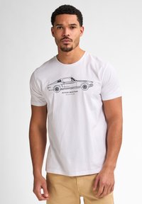 Hvid kortærmet t-shirt lavet af bomuld, der har en sort stregtegning af en klassisk bil med teksten "PETROE INDUSTRIES" nedenfor.