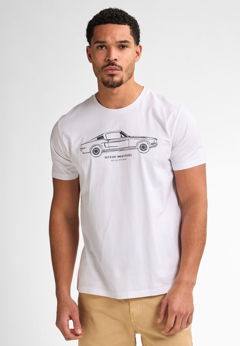 Hvid kortærmet t-shirt lavet af bomuld, der har en sort stregtegning af en klassisk bil med teksten "PETROE INDUSTRIES" nedenfor.