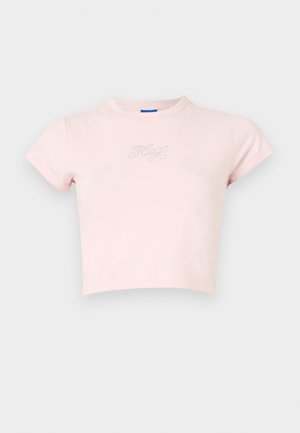 Camiseta rosa recortada de algodón, con mangas cortas y un pequeño diseño de texto plateado "Hug" en el pecho. Textura suave, cuello redondo.