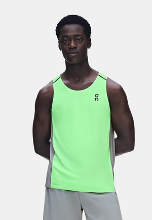 Jeune homme à la peau foncée et aux cheveux courts bouclés portant un débardeur sportif vert clair et un short gris clair.