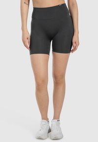 Pantaloni sportivi neri a vita alta realizzati in materiale elasticizzato, con una texture liscia e un design aderente, che terminano poco sopra la metà della coscia.