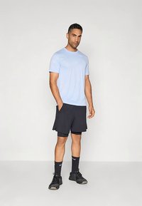 Lys blå trenings-t-skjorte, svarte shorts og svarte sportssokker. Har Nike-logo på skjorten og sokkene, samt teksturert shorts.
