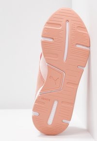 Suela de una zapatilla deportiva de goma rosa claro con patrones de agarre texturizados y una mediasuela blanca; presenta un logo y la marca "IGNITE."