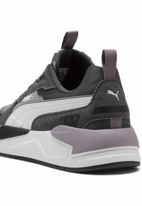 Scarpa sportiva grigia realizzata in materiali scamosciati e in rete, con dettagli bianchi, un collare imbottito e una suola in gomma testurizzata, caratterizzata da un elegante tacco viola.