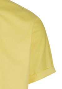 Camiseta amarilla de manga corta, hecha de algodón suave, con cuello redondo y puños de manga enrollados. Textura suave y diseño sencillo.