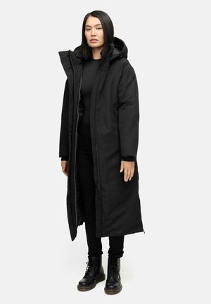 Lungo cappotto imbottito nero con cappuccio, realizzato in un tessuto liscio, dotato di zip completa e tasche laterali, indossato sopra una maglia e pantaloni neri.