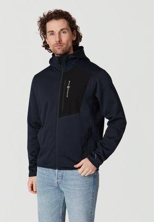 Tummansininen huppari, joka on valmistettu pehmeästä ja joustavasta kankaasta. Takissa on musta paneeli rinnassa ja vetoketjulliset taskut. Slim fit -muotoilu.