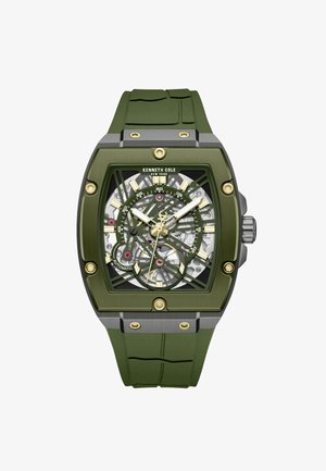 Kenneth Cole Uhr mit grünem Gummiband und einem rechteckigen Gehäuse aus Edelstahl, ausgestattet mit einem Skelett-Zifferblatt mit goldenen Akzenten und sichtbaren Zahnrädern.
