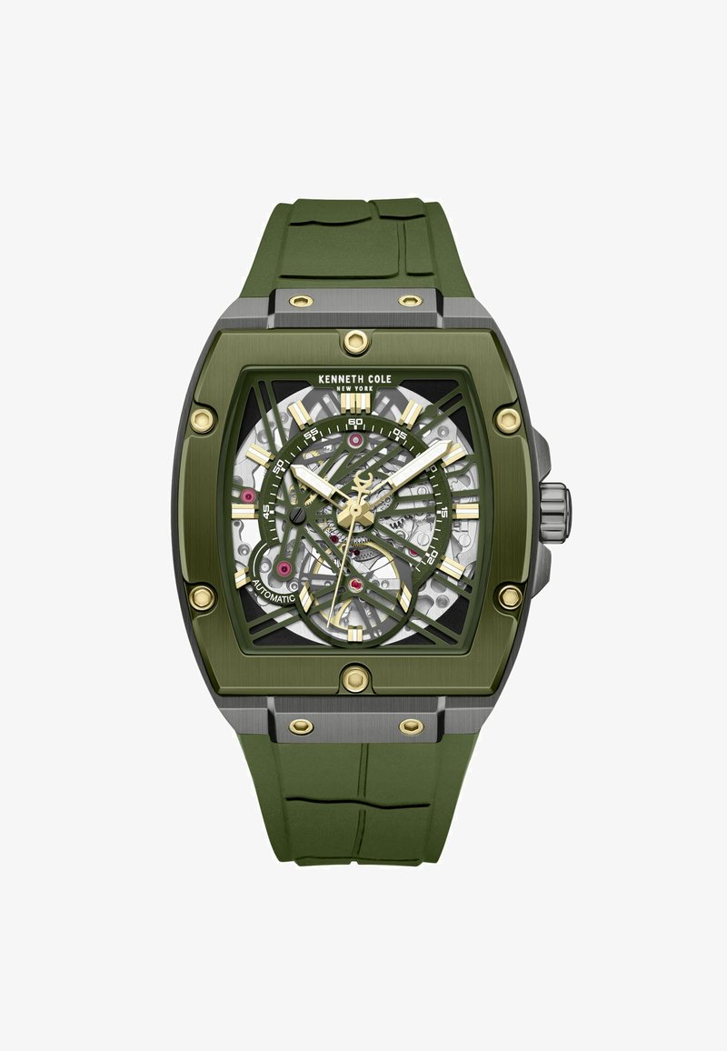 Montre Kenneth Cole avec un bracelet en caoutchouc vert et un boîtier rectangulaire en acier inoxydable, dotée d'un cadran squeletté avec des accents dorés et des rouages exposés.