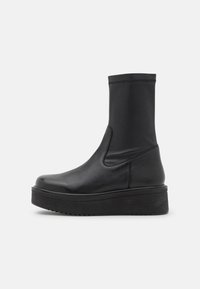 Bottes noires montant à la cheville, avec une tige en cuir, des panneaux latéraux élastiques, un bout arrondi et une semelle plateforme épaisse pour plus de hauteur.