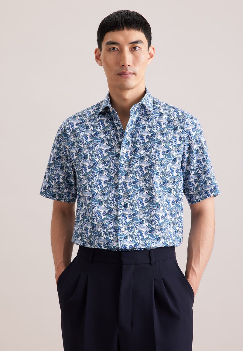 Kortarmig overhemd met een bloemenpatroon in blauw, wit en groen. Voorzien van een button-down kraag en een ontspannen pasvorm, gecombineerd met donkere broek.