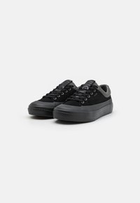 Zapatillas negras con parte superior de ante suave, puntera redonda, detalles de malla gris, cordones planos y suela de goma texturizada.