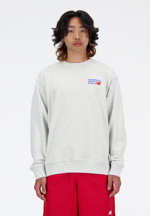 Sudadera gris con puños y dobladillo acanalados, que presenta un logo multicolor de "New Balance" en el lado izquierdo del pecho. Tejido de mezcla de algodón.