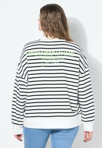 Sudadera a rayas en blanco y negro con corte holgado. Cuenta con un gráfico en verde neón que dice "SUNDAY BRUNCH CLUB" en la parte posterior. Tela suave, puños de canalé.