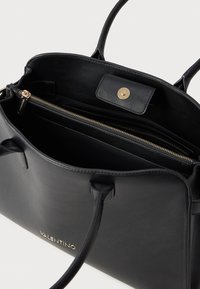 Czarna skórzana torebka z złotymi akcentami. Posiada kieszeń na zamek błyskawiczny i magnetyczne zapięcie. Prosty, elegancki design z widocznym logo marki.