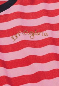 Rotes und pink gestreiftes Stoffhemd mit einem abgerundeten schwarzen Kragen. Verfügt über goldene gestickte Schriftzüge mit dem Wort "imagine". Weicher Stoff, lässiges Design.