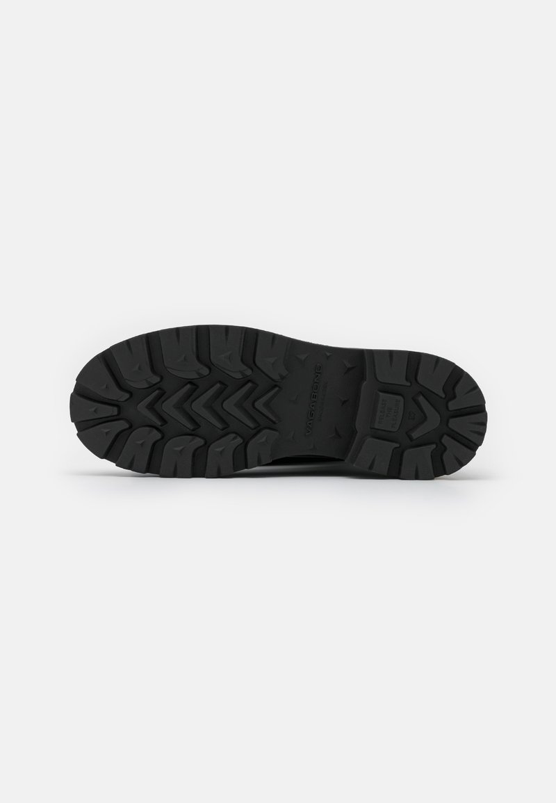 Semelle en caoutchouc noir avec un motif de semelle robuste comportant des rainures multidirectionnelles et des sections surélevées pour une adhérence et une traction optimales.