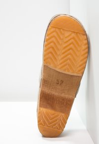 Beige suede shoe sole with diagonal grooves, orange rubber, and embossed size 37 on a wooden section. Clean, minimal design.