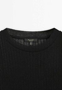 Pull en maille côtelée noire avec encolure ronde et une étiquette visible indiquant la taille M pour EUR, USA et MEX.