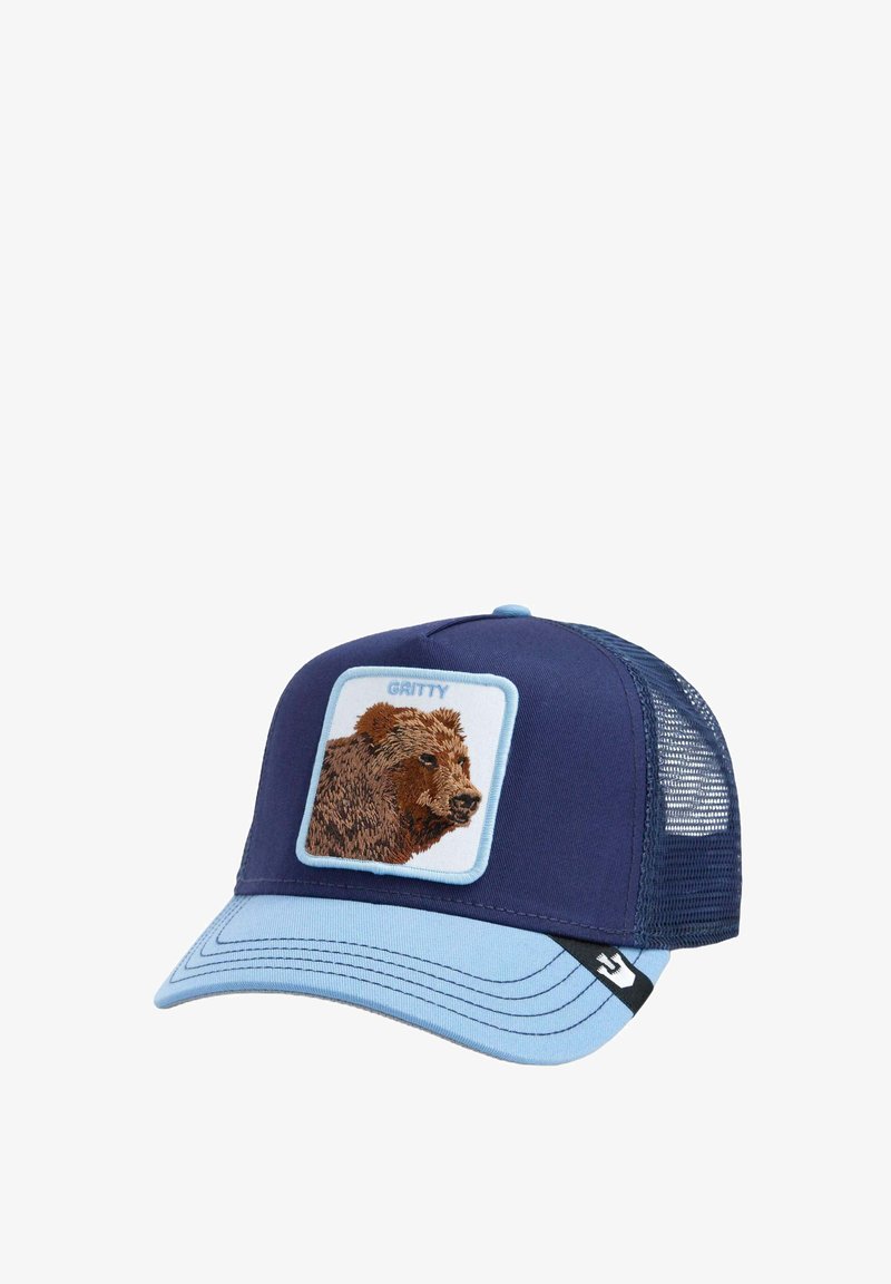 Navy blue trucker hat with embroidered bear patch in beige and brown. Light blue bill and mesh back. Features black logo tag on side.