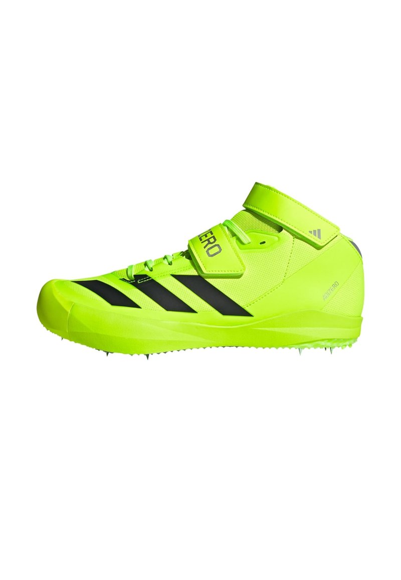 Baskets de sport vert vif avec des rayures noires, tige en synthétique, fermeture à lacets et Velcro, bout rond et semelle à picots pour une meilleure adhérence.