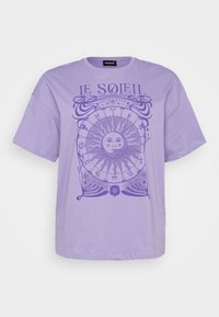 Camiseta de algodón lavanda con mangas cortas, que presenta un gráfico circular de sol y símbolos astrológicos en un púrpura más oscuro. Cuello redondo.
