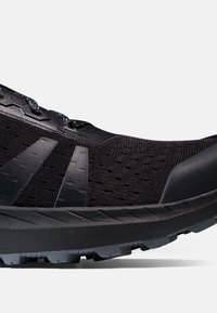 Svart löparskor med ett texturerat meshtunika, förstärkt tåskydd och gummisula med ett räfflat mönster för grepp.