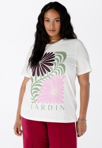 Korte mouwen crème t-shirt met een grote bloemafbeelding in bordeauxrood, groen en roze, met het woord "JARDIN" eronder gedrukt. Soepele stof.