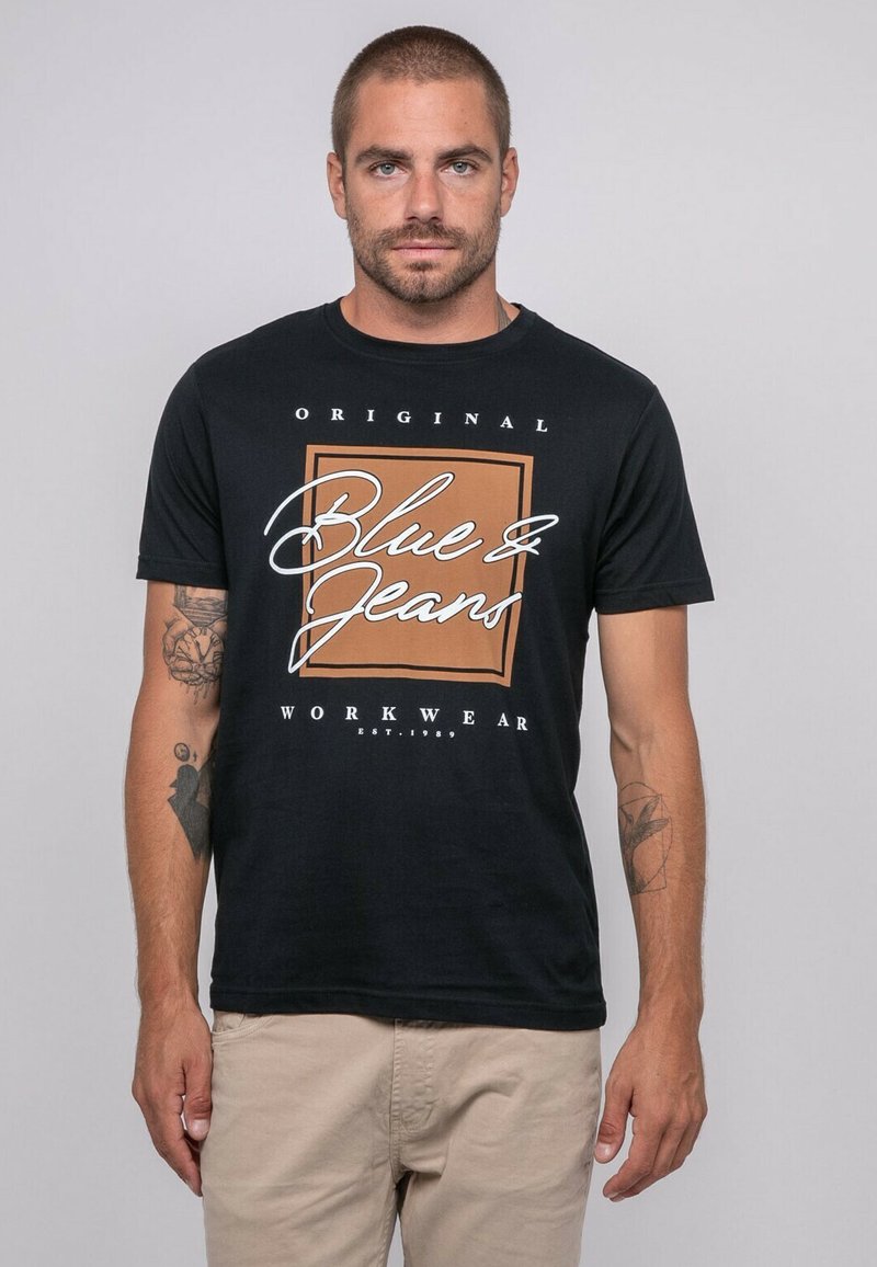 T-shirt en coton noir avec un design graphique portant l'inscription "Blue & Jeans" en blanc et orange, à manches courtes et col rond classique.