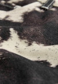 Gros plan sur un tissu avec un motif abstrait noir et blanc et un tissage texturé visible.