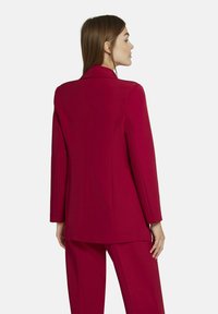 Aansluitende magenta blazer met een gestructureerde silhouet, lange mouwen, notch revers en een gladde textuur, gecombineerd met bijpassende broek.